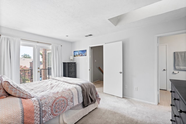 bedroom with access to outside, light colored carpet, and a textured ceiling