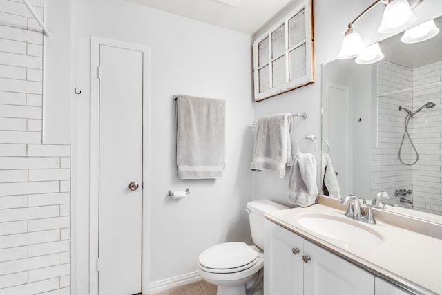 bathroom featuring toilet, a tile shower, and vanity