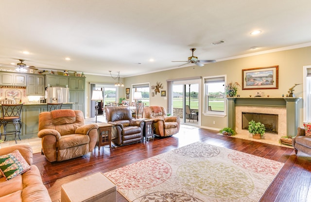 living room featuring a fireplace, crown molding, and ceiling fan with notable chandelier