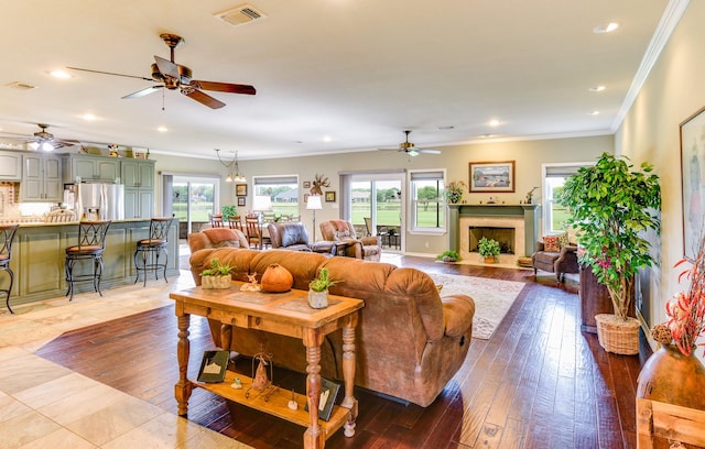 living room with light hardwood / wood-style floors, a wealth of natural light, ornamental molding, and ceiling fan