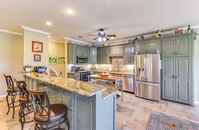 kitchen featuring a kitchen breakfast bar, kitchen peninsula, ornamental molding, and stainless steel appliances