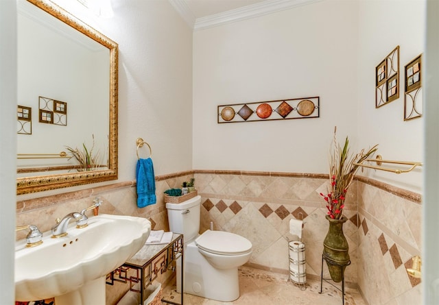 bathroom with toilet, tile walls, tile patterned floors, sink, and crown molding