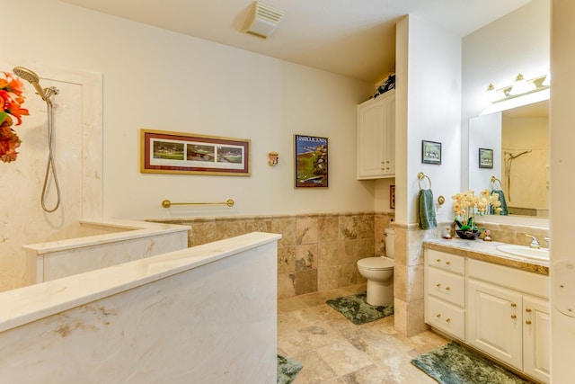 bathroom featuring tile walls, toilet, and vanity