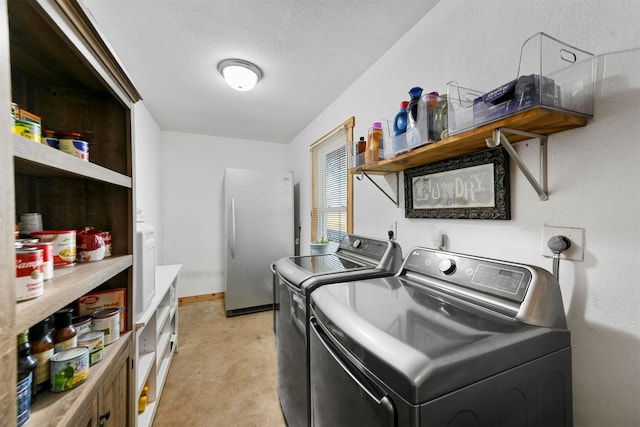 clothes washing area with washing machine and clothes dryer and a textured ceiling