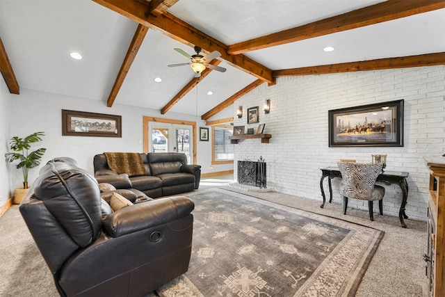 living room with a brick fireplace, ceiling fan, vaulted ceiling with beams, and carpet floors