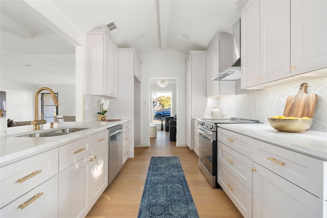 kitchen with appliances with stainless steel finishes, light stone countertops, wall chimney exhaust hood, white cabinets, and sink