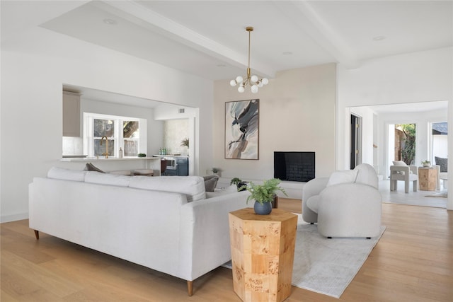 living room featuring light wood-type flooring, a notable chandelier, and beamed ceiling