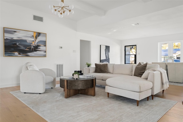 living room featuring light wood-type flooring, a chandelier, and beamed ceiling