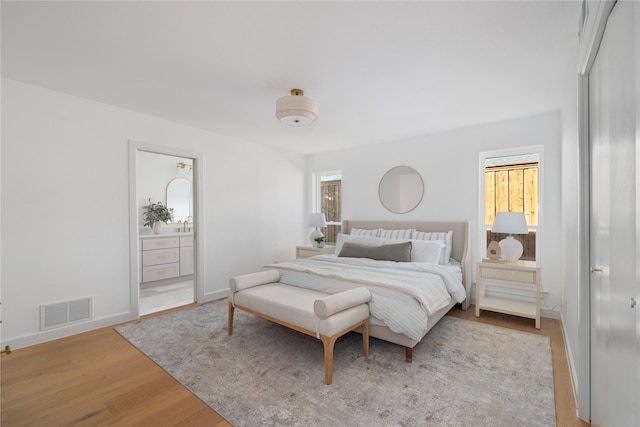 bedroom featuring connected bathroom and light hardwood / wood-style flooring