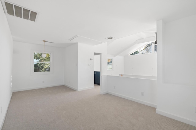 carpeted spare room with vaulted ceiling