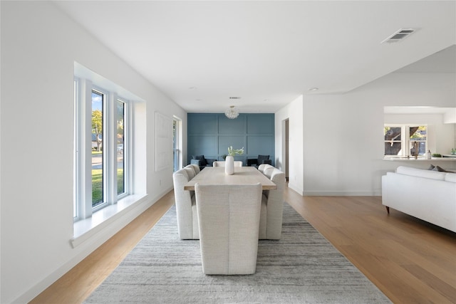 dining area with light wood-type flooring, plenty of natural light, and a notable chandelier