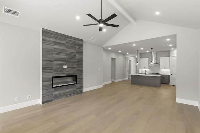 unfurnished living room with ceiling fan, sink, a fireplace, and light hardwood / wood-style floors