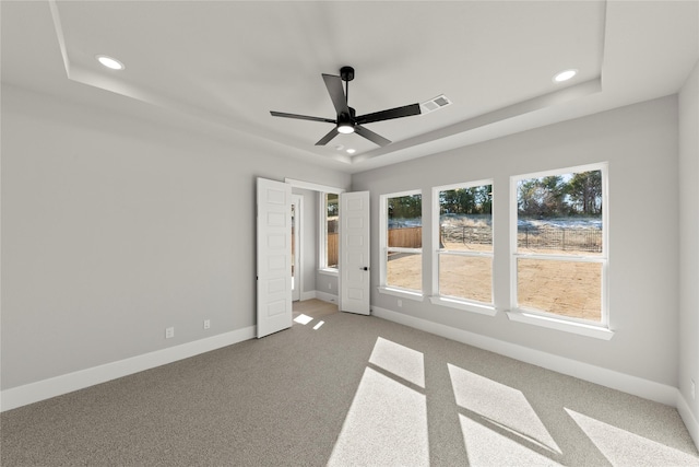 unfurnished bedroom featuring a raised ceiling, carpet floors, and ceiling fan