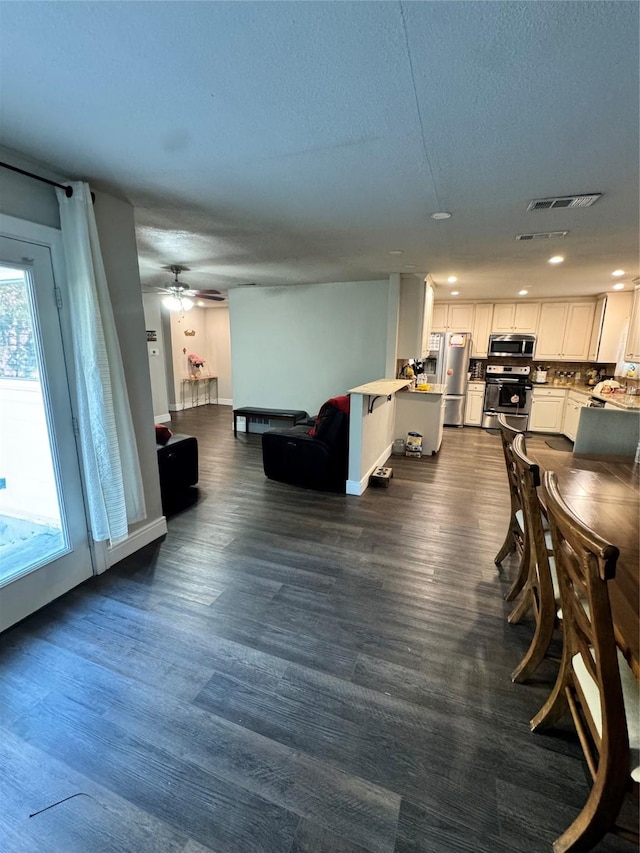 living room featuring ceiling fan, plenty of natural light, a textured ceiling, and dark hardwood / wood-style flooring