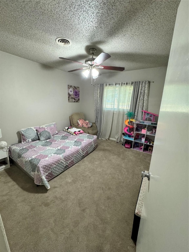 bedroom with ceiling fan, carpet floors, and a textured ceiling