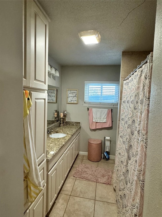 bathroom with a textured ceiling, vanity, and tile patterned flooring