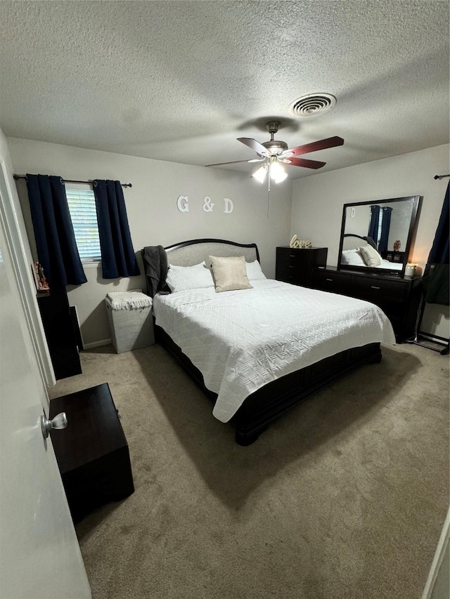 carpeted bedroom with ceiling fan and a textured ceiling