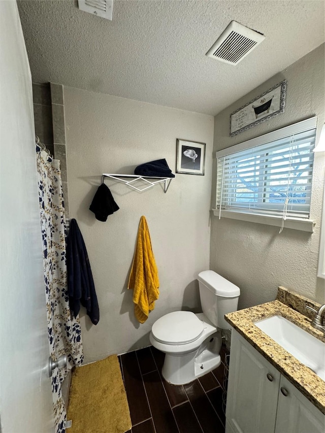 bathroom with toilet, vanity, a shower with shower curtain, and a textured ceiling