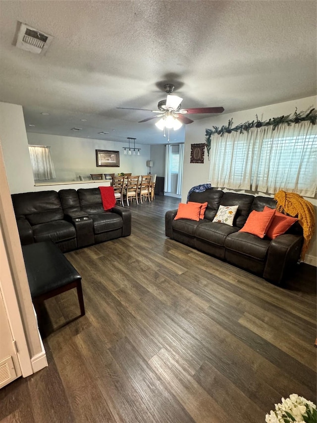 living room with ceiling fan, a textured ceiling, and dark hardwood / wood-style flooring