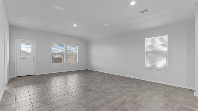 tiled empty room featuring vaulted ceiling