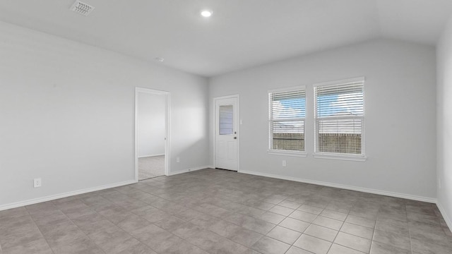 empty room with light tile patterned floors and lofted ceiling