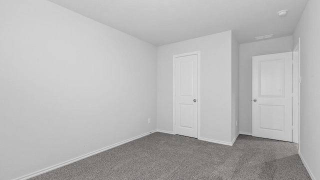 unfurnished bedroom with dark colored carpet and a closet