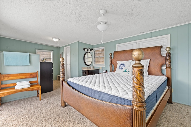 bedroom featuring ceiling fan, light colored carpet, a textured ceiling, and ornamental molding