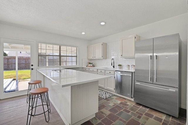 kitchen with a kitchen breakfast bar, appliances with stainless steel finishes, sink, and white cabinetry