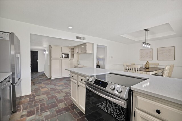 kitchen with white cabinetry, appliances with stainless steel finishes, a raised ceiling, light stone countertops, and pendant lighting