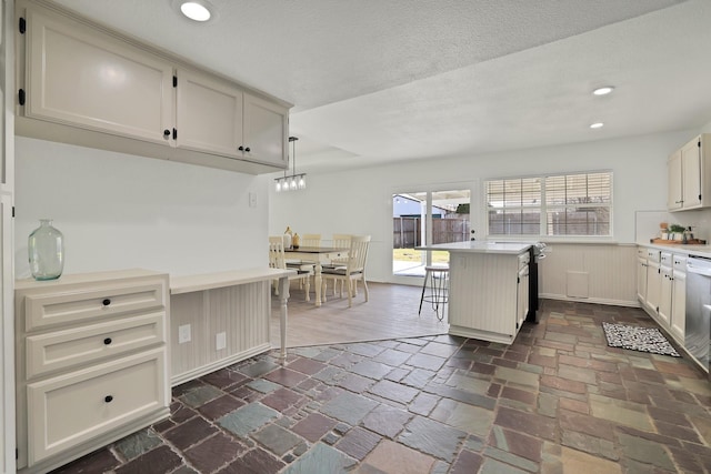 kitchen featuring a kitchen breakfast bar, a textured ceiling, and hanging light fixtures