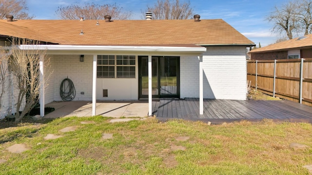 back of house with a deck, a lawn, and a patio