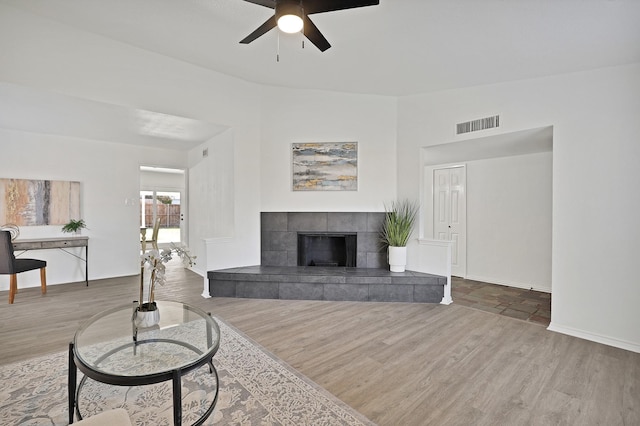 living room with ceiling fan, hardwood / wood-style flooring, and a tile fireplace