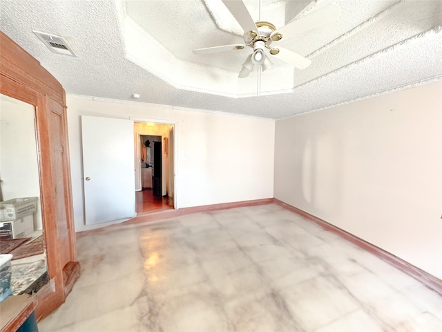 empty room featuring concrete floors, a textured ceiling, a raised ceiling, and ceiling fan