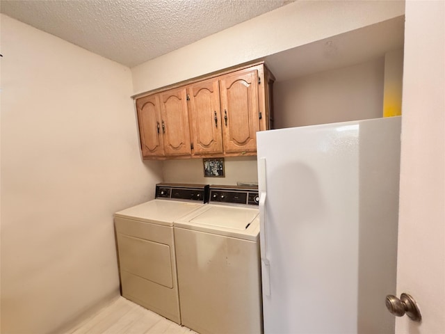 laundry room with cabinets, a textured ceiling, and washer and clothes dryer