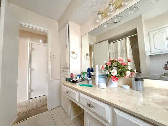 bathroom featuring a textured ceiling, vanity, and tile patterned flooring