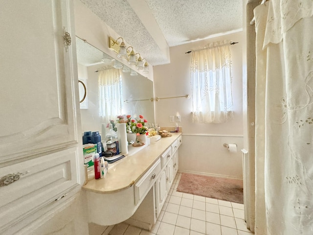 bathroom with a textured ceiling, tile patterned flooring, and vanity