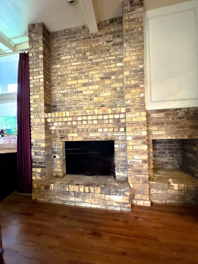 room details featuring a brick fireplace, beam ceiling, and hardwood / wood-style floors