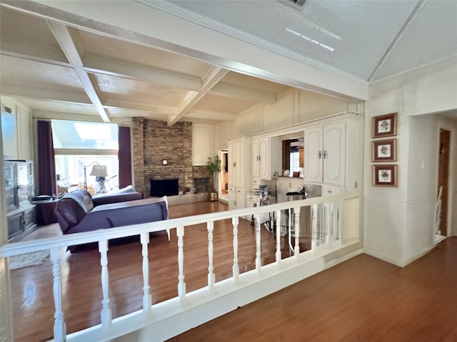 living room with hardwood / wood-style floors, coffered ceiling, beamed ceiling, and a fireplace