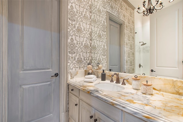 bathroom with a shower, an inviting chandelier, vanity, and wallpapered walls