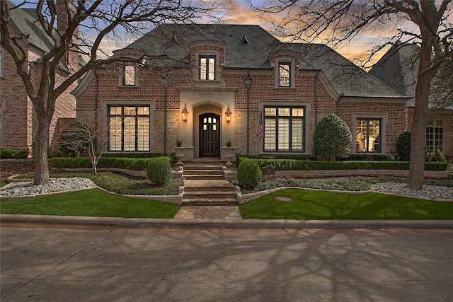 french provincial home with brick siding and stone siding