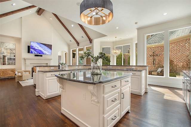 kitchen featuring a kitchen island, open floor plan, beam ceiling, a fireplace, and a peninsula