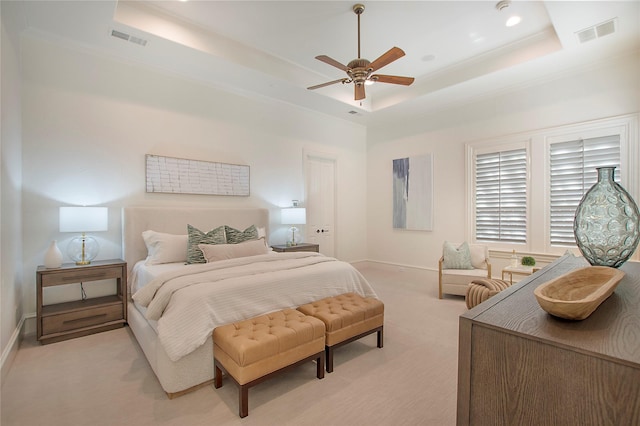 bedroom with a tray ceiling, visible vents, and light carpet