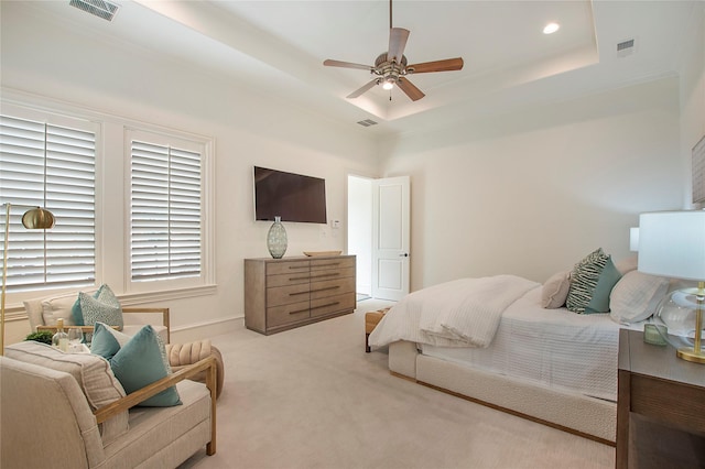 carpeted bedroom with visible vents, a raised ceiling, and ceiling fan