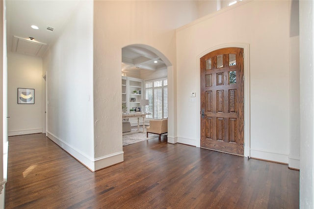 foyer featuring beam ceiling, coffered ceiling, arched walkways, baseboards, and dark wood-style flooring