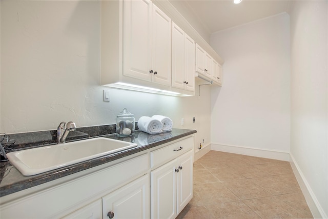 clothes washing area with light tile patterned floors, cabinet space, baseboards, and a sink