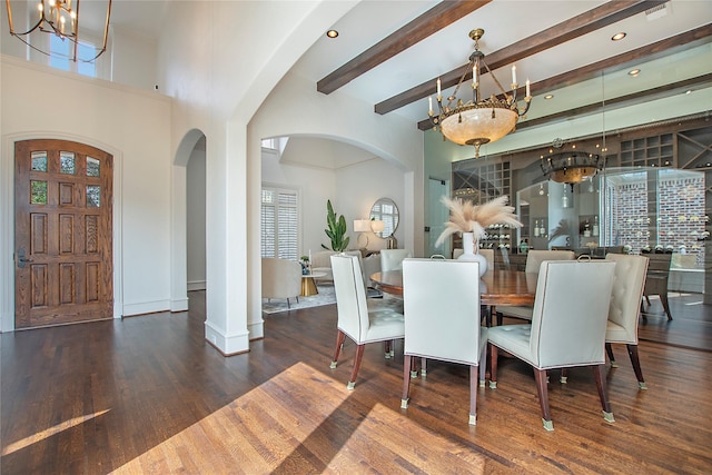 dining room featuring a chandelier, beam ceiling, arched walkways, and wood finished floors