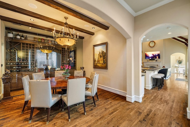 dining area with beam ceiling, hardwood / wood-style floors, and crown molding