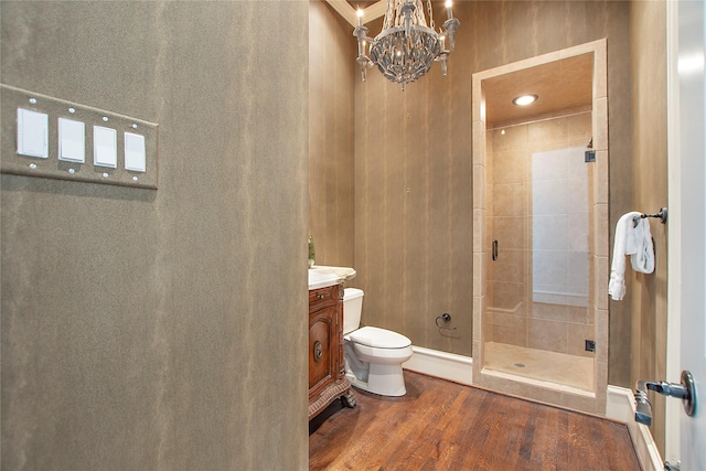 bathroom with vanity, wood finished floors, a shower stall, toilet, and a chandelier