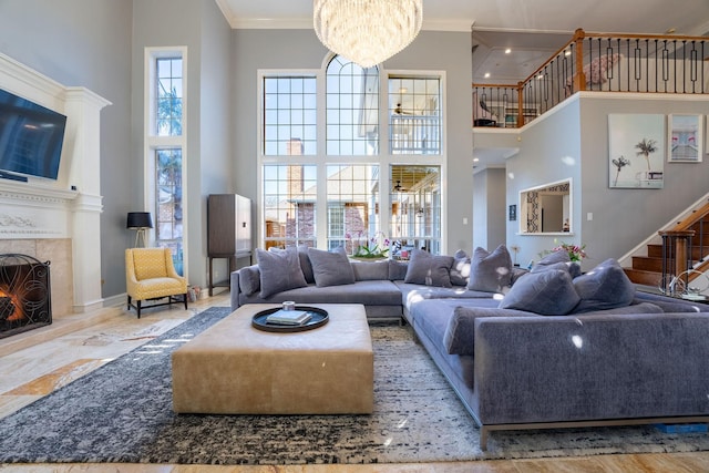 living room featuring a towering ceiling, ornamental molding, a fireplace, and a notable chandelier