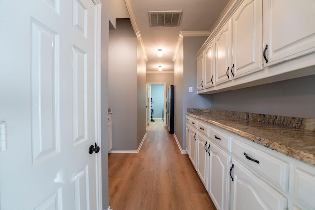 hallway with light hardwood / wood-style flooring and crown molding